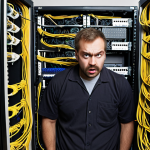 **A network administrator looking overwhelmed at a messy, undocumented network rack. Cables are everywhere, and there are no labels. Humorous, slightly exaggerated style.**